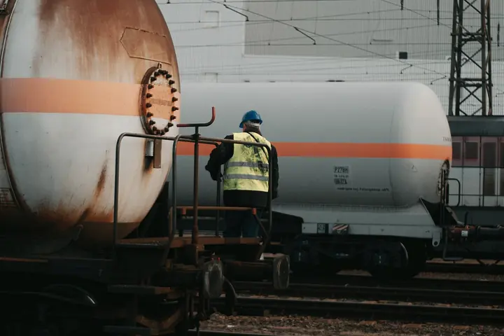 Yük treni vagonları arasında reflektif yelekli demiryolu çalışanı